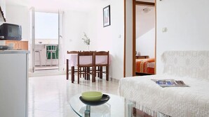 A living room with a glass coffee table, a sofa, a dining area with a table and chairs, and a kitchen area with a refrigerator and a television. - Apartment 2024/28742 (Istria - Rabac), 1200m from the beach (Rabac)