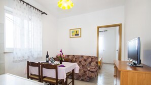 A dining area with a table, chairs, a sofa, a television, and a refrigerator. - Apartment 2024/28743 (Istria - Rabac), 1200m from the beach (Rabac)