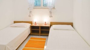 A twin room with two single beds, a small table, a nightstand, a window with curtains, and a rug. - Apartment 2024/28745 (Istria - Rabac), 1200m from the beach (Rabac)