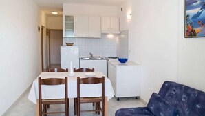 A compact kitchen with white cabinets, a dining table with chairs, and a blue sofa. - Apartment 2024/28745 (Istria - Rabac), 1200m from the beach (Rabac)