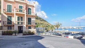 A multi-story building with balconies, a parking area, and a marina in the background. - Awesome apartment in Castellammare d.G. with WiFi (Castellammare d.G.)