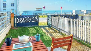 Un patio con una mesa, sillas, una tetera y una taza de té.