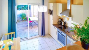 Una cocina funcional con microondas, estufa y horno. Hay una mesa de comedor con sillas y una ventana con cortinas.