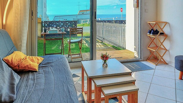 Una sala de estar moderna con un sof á, una mesita y vistas a un balcón con una silla y una mesa.