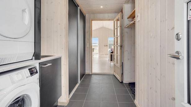A laundry room with a washing machine, dryer, and cabinets. - Nice home in Løkken with sauna (Løkken)