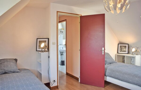 A bedroom with two beds, a red door, and a ceiling light fixture.