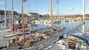 Un port de plaisance où sont amarrés de nombreux voiliers, un bâtiment avec un toit rouge et un ciel dégagé.