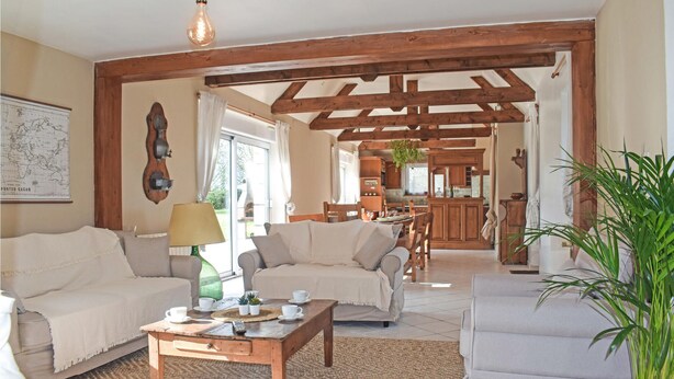 Un vaste salon doté d’un plafond en bois, un coin repas et une cuisine ouverte sur le salon.