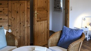 A cozy room with wicker furniture, a white table with a book, and a wooden door. - Vacation home Queller 14, fenced garden, Wlan - Holiday home Queller 14 (Friedrichskoog)