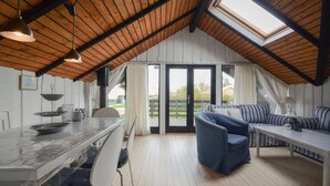 Un espace de vie chaleureux et ouvert, comprenant un coin cuisine, une table à manger et un coin salon avec un canapé et des fauteuils.