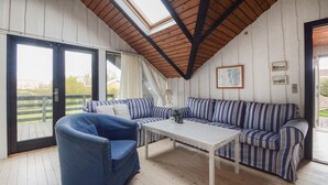 Une pièce chaleureuse avec un plafond en bois, un canapé à rayures, un fauteuil bleu et une table.