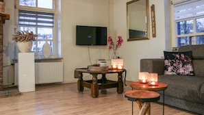 A living room with a wooden floor, a sofa, a coffee table, a TV, and a fireplace.