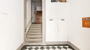 A staircase leading to a room with a checkered floor, white walls, and a wooden door.