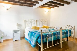 A bed with a metal frame and a blue and white checkered bedspread, a bedside table with a lamp, and a small potted plant. - GuestHost - Comfortable and characteristic 55sqm apartment that can accommodate up to 4 people. Located on the mezzanine floor (two flights of stairs to access) of an ancient Florentine building, the apartment is located on the lower slope of Bardini Gar (Florence)