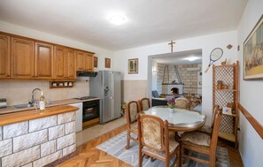Une cuisine dotée de meubles en bois, d’un réfrigérateur, d’une cuisinière et d’un coin repas avec une table et des chaises.