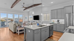 Una cocina moderna con armarios grises, una isla central y un área de comedor con sofá y mesa.