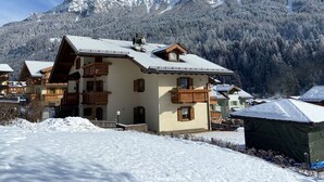 Un edificio in stile chalet con tetto spiovente, balconi in legno e montagne sullo sfondo.