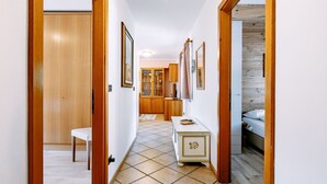 Un corridoio con porte in legno, una panca bianca, una toeletta con specchio e un letto sullo sfondo.