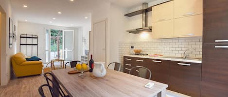 A modern kitchen with wooden cabinets, a built-in stove, and a dining area with a wooden table and chairs.