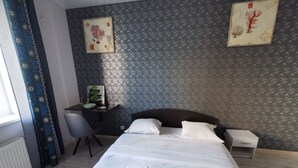 A hotel room with a neatly made bed, a desk with a chair, and two framed botanical prints on the wall. - Have your own privacy with total comfort at a very low price. (Kyiv)