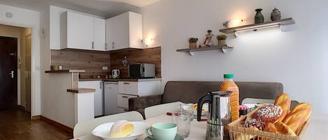 A compact living space with a kitchenette, dining area, and a sofa.
