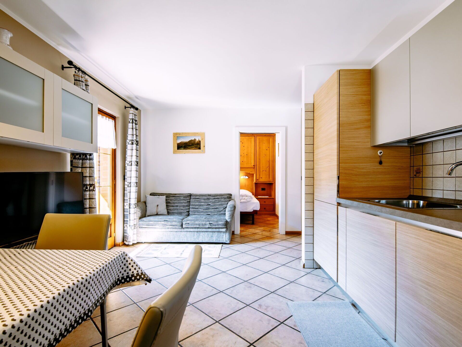 A compact living space with a kitchenette, a sofa, a dining table, and a TV.