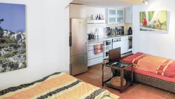 Una habitación pequeña con cama, una mesita, una silla y un rincón americano.