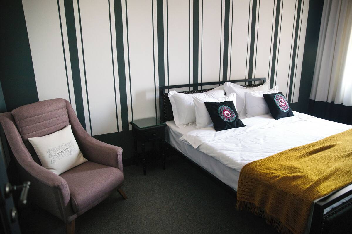 Une chambre d’hôtel avec un lit, une chaise et une table de chevet.