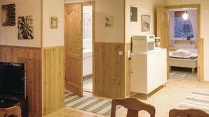 Ein Zimmer mit Holzboden, einem Bett mit Fenster, einer Mikrowelle und einem kleinen Schrank.