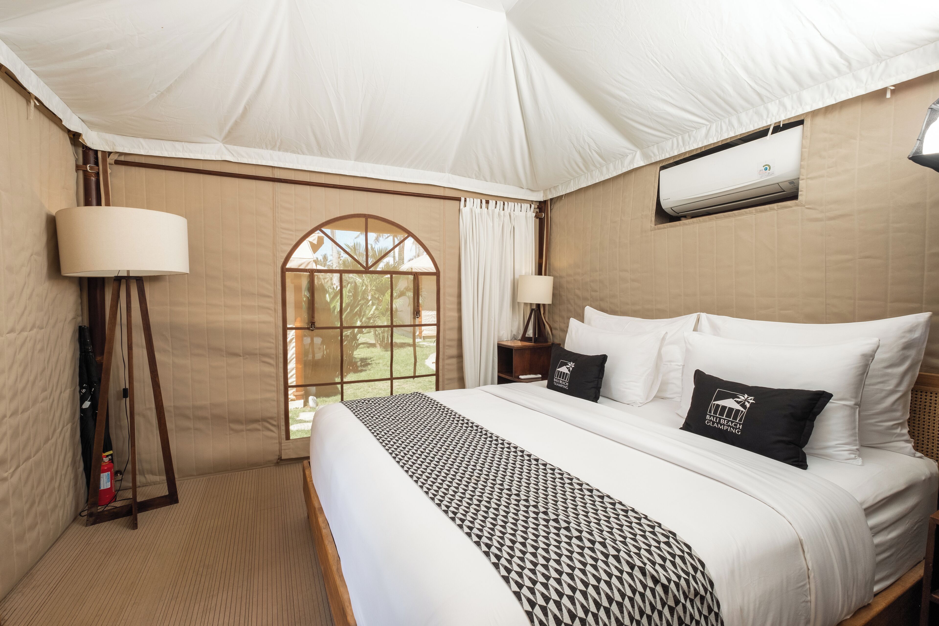Una habitación con carpa, una cama, dos lámparas de noche, una ventana y un equipo de aire acondicionado.