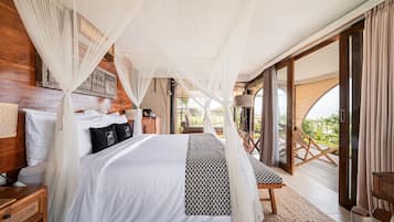 A bedroom with a bed, bedside tables, a bench, and a view of the outdoors.