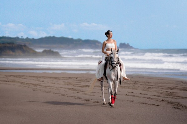 A person riding a horse on a beach with waves in the background. - Bali Beach Glamping (Tabanan)