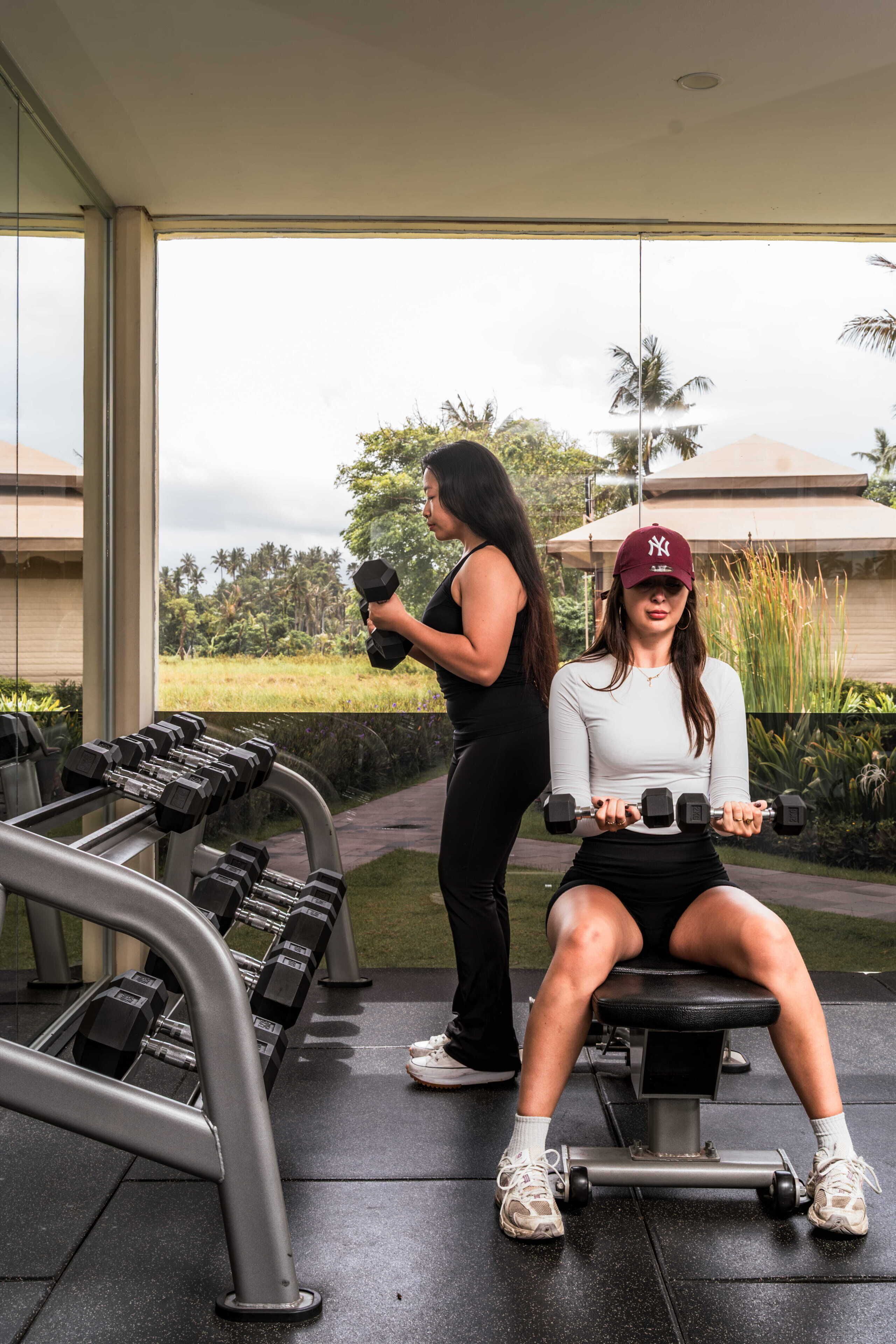 A gym with exercise equipment, a bench, and a person sitting on the bench.