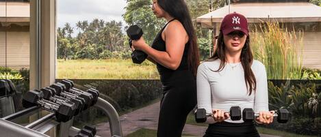 A gym with exercise equipment, a bench, and a person sitting on the bench.
