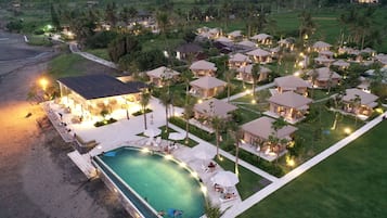 Relax by the resort's central pool surrounded by lush lawns and palm trees.
