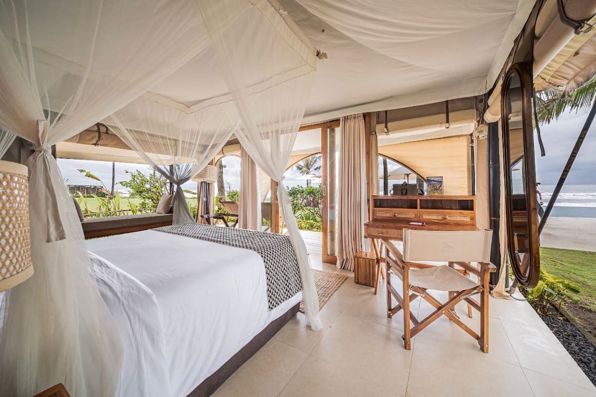 A bedroom with a bed, a desk, and a view of the beach.