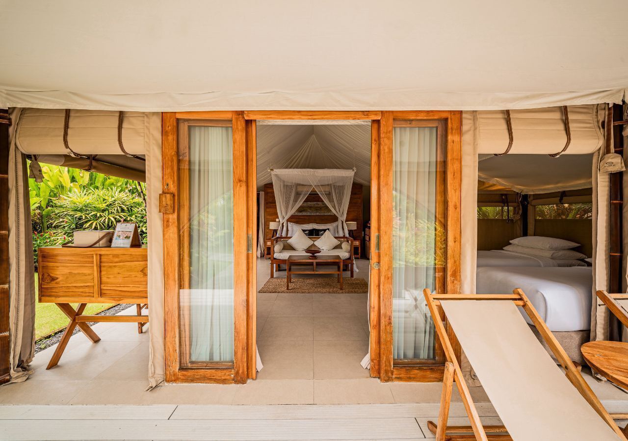 A tented room with a bed, a sofa, and a wooden table.