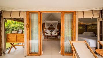 A tented room with a bed, a sofa, and a wooden table.