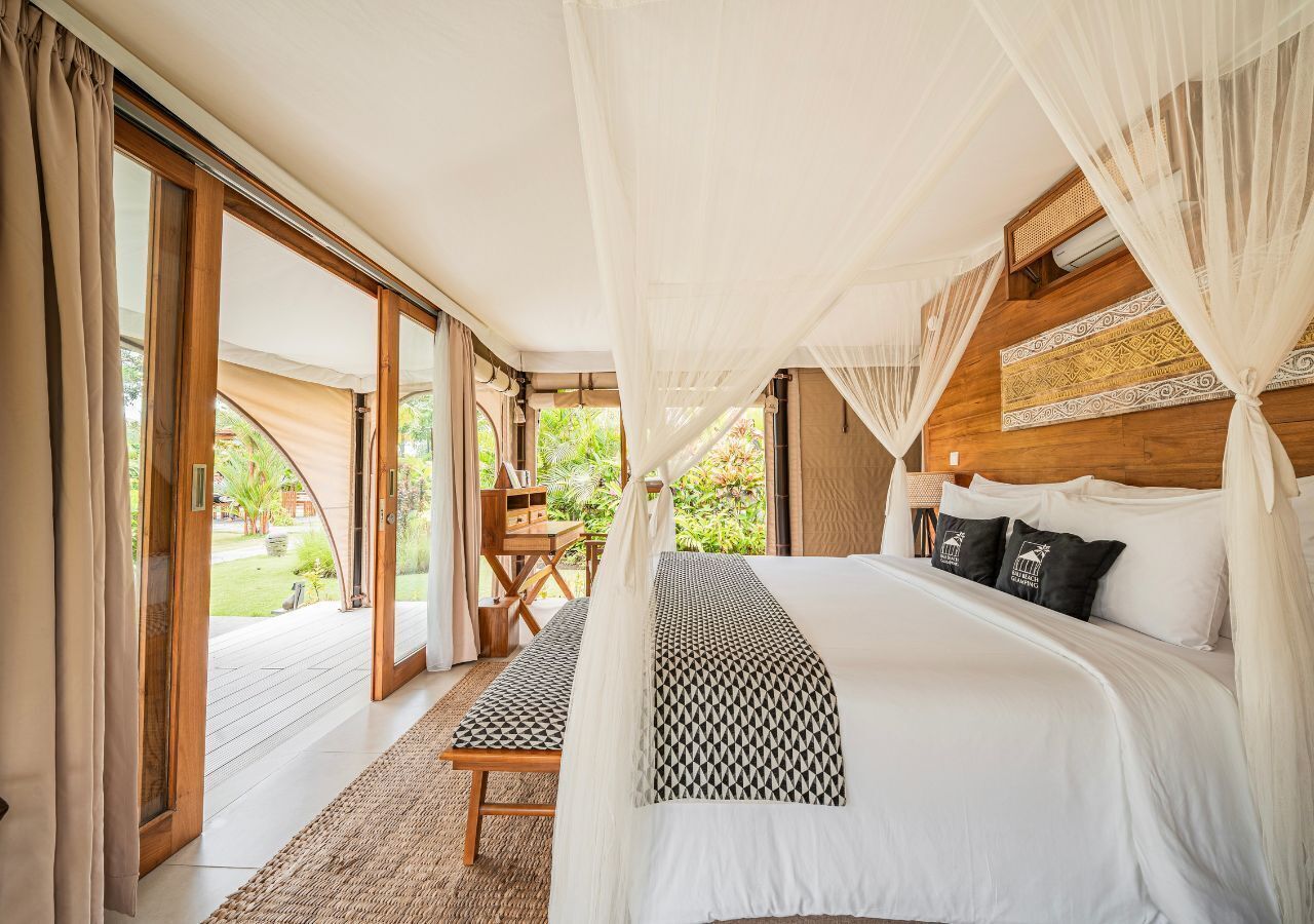 A bedroom with a large bed, a wooden headboard, and a view of the outdoors.