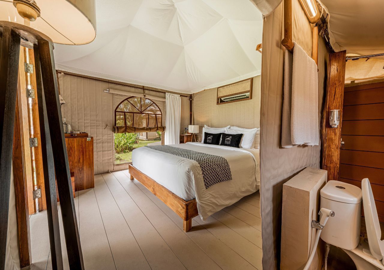 Un dormitorio con una cama grande, cabecera de madera y vista a zonas verdes.