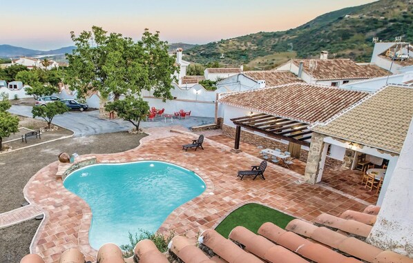 A pool area with a clear view of the surrounding landscape, including houses and a hilly background.