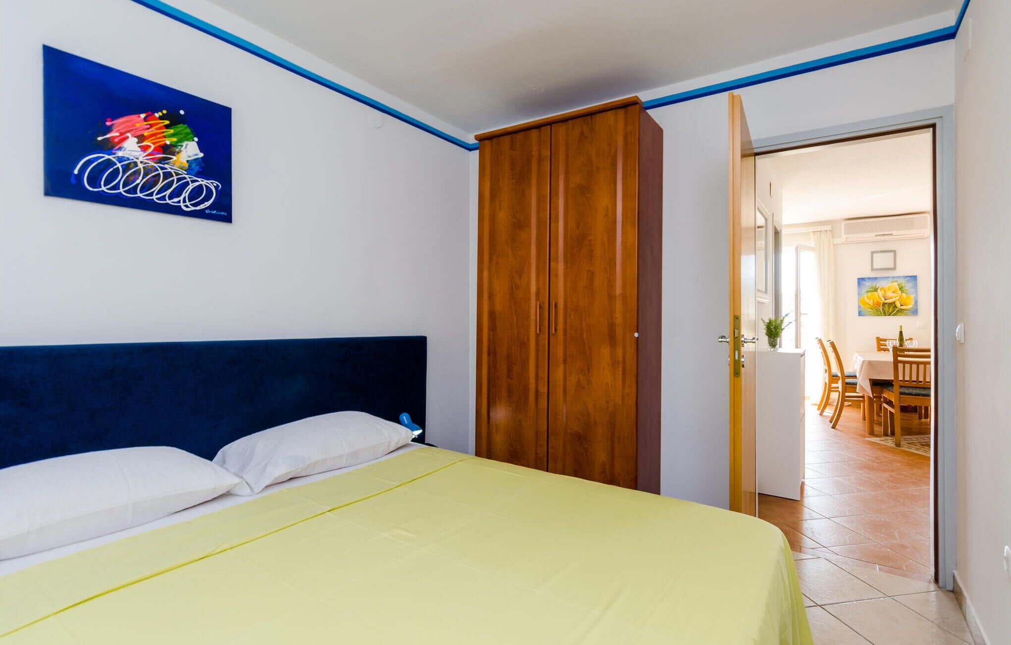 A bedroom with a bed, a wardrobe, and a painting on the wall.
