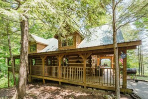 A cabin with a deck, a covered porch, and a grill area.