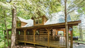 A rustic cabin with a wooden deck, a covered porch, and a view of the surrounding forest. - Big Kahuna Lodge 3 Bedroom Cabin by RedAwning (Sevierville)