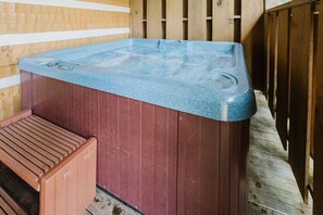 Un jacuzzi con revestimiento de madera y un banco a su lado.