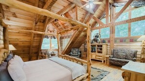 A log cabin bedroom with a bed, a sofa, a desk, and a chair. - Big Kahuna Lodge 3 Bedroom Cabin by RedAwning (Sevierville)