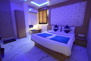 A modern hotel room with a large bed, a desk, and a wardrobe. - Hotel New Pathik (Ahmedabad)