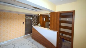 Una zona d'entrada moderna amb un sòl de marbre, una taula de recepció de fusta i una paret amb un disseny decoratiu.