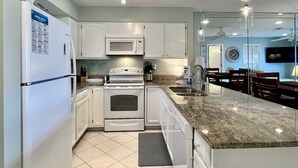 Een moderne keuken met witte kasten, een inbouwoven, een magnetron en een granieten aanrecht.