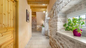 Un couloir étroit aux murs en bois, avec un mur de pierre d’un côté et une fenêtre au fond.